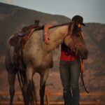 A woman standing next to a horse in a field